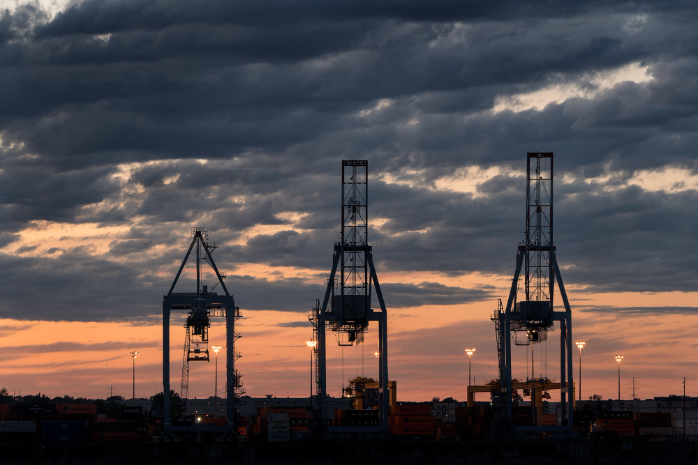 Container cranes at an energy and logistics port in Indonesia during sunset, representing energy infrastructure development.